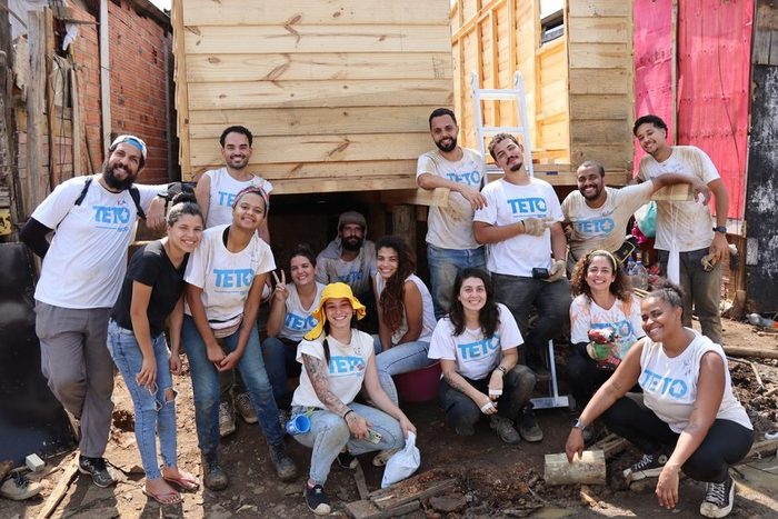 Grupo de voluntários posando na frente da casa de madeira finalizada